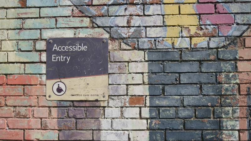 Schild Accessible Entry auf Wand, um die Relevanz der Barrierefreiheit zu zeigen
