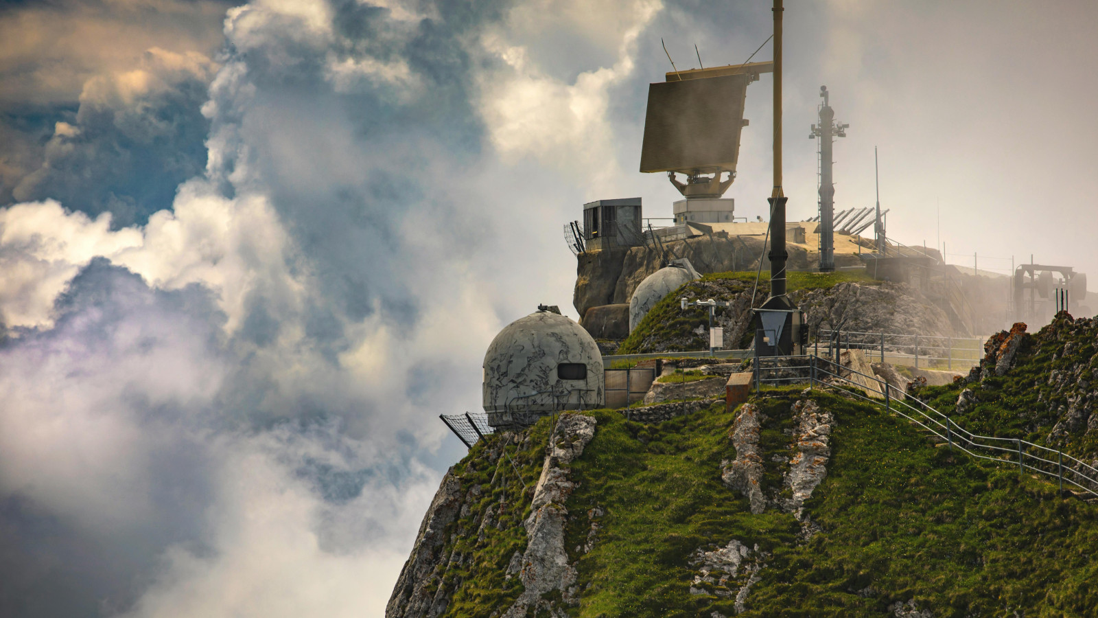 Radaranlage mit rotierender Antenne auf einem bewölkten Berggipfel