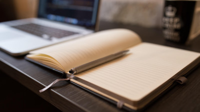 Laptop und aufgeklapptes Buch auf einem Schreibtisch