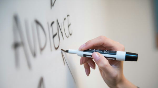 Hand zeichnet einen Pfeil in Richtung auf das Wort Audience auf einem White Board